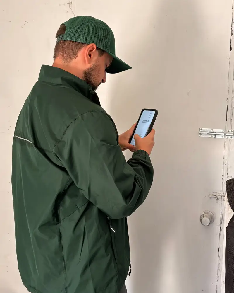 Doody Free scooper photographing a latched gate bolt with a phone before leaving a Federal Way yard